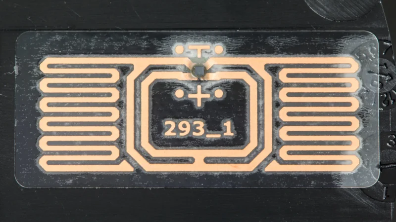 Elektronik cihaz kasasına uygulanmış anteni ve çipi görünen gerçek RFID etiketi.